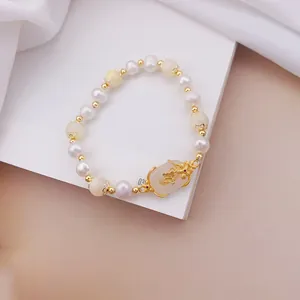 Primo piano di un braccialetto di perle con occhio di gatto e ciondolo floreale d'oro