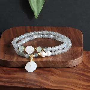 Nahaufnahme eines zweireihigen Natursteinarmbands mit einem weißen Jade-Anhänger