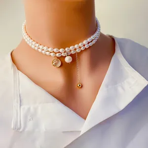 Gros plan du collier ras-du-cou en perles avec breloque cerf et pampille dorée