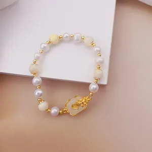 Dettaglio di bracciale con perle e occhio di gatto con elegante farfalla dorata