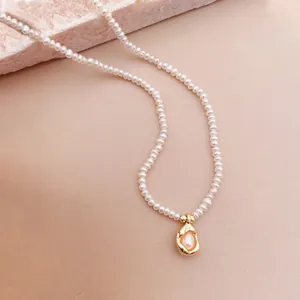 Detailansicht einer minimalistischen französischen Süßwasserperlenkette mit Goldanhänger.