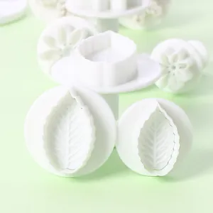 Close-up detail of white plastic leaf-shaped fondant embossing molds for DIY baking