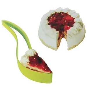 Handheld green plastic cake slicer and server tool holding a slice of strawberry cake