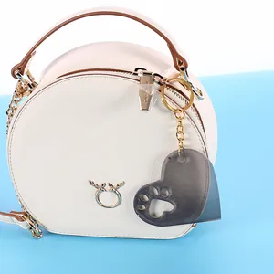Close-up of a dark gray heart-shaped cat paw silicone mold hanging as a charm on a white bag