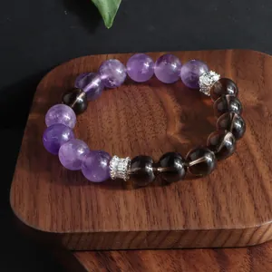 Detalle de una pulsera de amatista natural y cuarzo ahumado en un soporte de madera