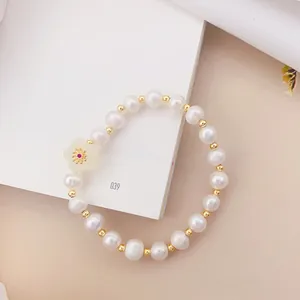 Primo piano di un elegante braccialetto di perle occhio di gatto bianco con ciondolo a fiore