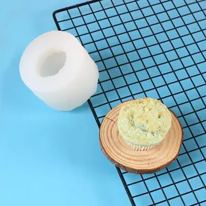 Witte siliconen muffin cup vorm met afgewerkte groene cupcake gepresenteerd op houten schijf