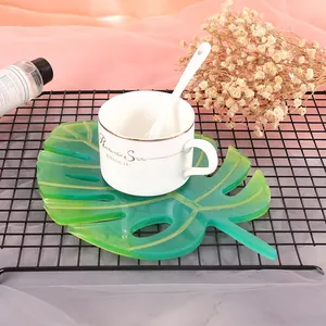 Gros plan sur un sous-verre en résine en forme de feuille de monstera verte sur un support