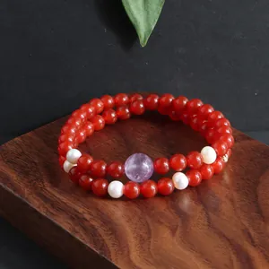 Gedetailleerde opname van een dubbelstrengs rood kristallen armband met kunziet en parels