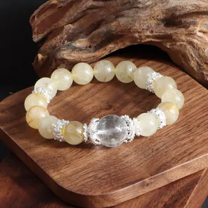 Detalle macro de una pulsera de cuarzo rutilado dorado en un soporte de madera decorativo Zen