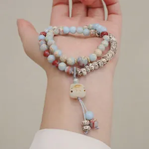 Primo piano del bracciale di perline multistrato con un grazioso ciondolo a gatto in giada