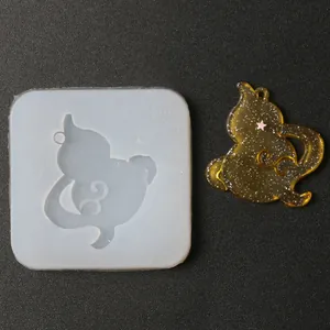 Detailed view of cat shape silicone mold alongside a finished amber glitter resin cat pendant