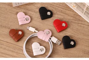 Multiple colorful heart-shaped PU leather cable organizers shown on a warm wooden desk