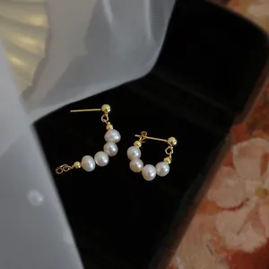 Primer plano detallado de elegantes pendientes dorados vintage con perlas blancas.