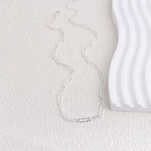 Detailed view of textured silver sparkly link necklace on minimalist white background