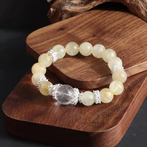 Primer plano de pulsera de cuarzo rutilado dorado con detalles plateados en madera