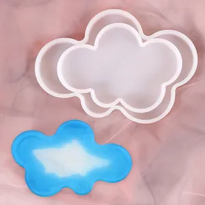 Close-up view of a cloud-shaped silicone coaster mold and a finished blue resin coaster.