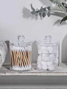Détail de deux bocaux en acrylique transparents pour cotons sur une étagère rustique