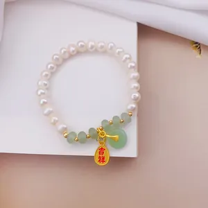 Macro dettaglio di un bracciale di perle e occhio di gatto con ciondoli portafortuna