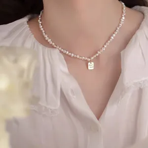 Primer plano de collar de perlas barrocas con colgante dorado Good Luck