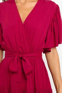 Close-up detail of a magenta V-neck summer dress with ruffled sleeves and tie waist