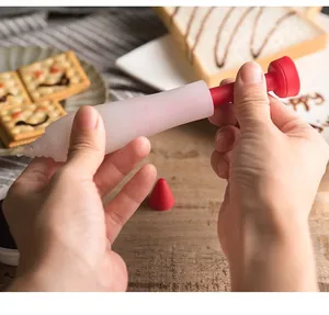 Macro view of hands holding a red and white silicone cake decorating pen for writing