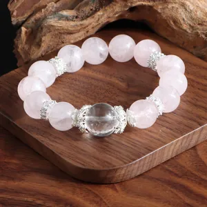 Détail d'un bracelet en perles de quartz rose et cristal de roche sur socle en bois