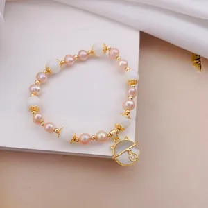 Vista macro dettagliata del bracciale con pietre occhio di gatto e ciondolo gatto dorato.