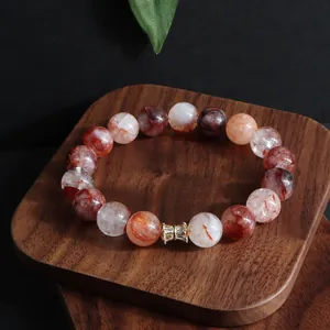 Detailansicht eines 12mm Kristallarmbands mit goldenem Zirkonia-Anhänger auf dunklem Holz