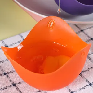 Vista macro di una tazza di camicia per uova in silicone arancione con un uovo crudo su tela
