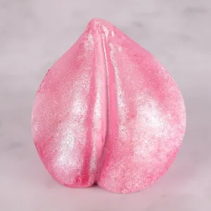 Primer plano de una vela rosa en forma de melocotón con un acabado brillante y fino