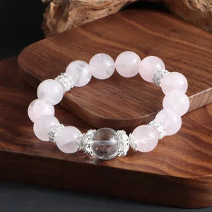 Détail en gros plan montrant les perles de quartz rose et le cristal sur support bois.