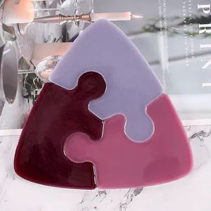 Close-up of three interlocking puzzle piece coasters in purple and burgundy resin