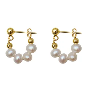 Detalle de elegantes pendientes de oro y perlas con agujas de plata s925.
