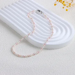 Détail d'un collier de perles de nacre multicolores sur un support texturé blanc