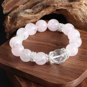 Gros plan d'un élégant bracelet en quartz rose et cristal blanc sur un support en bois