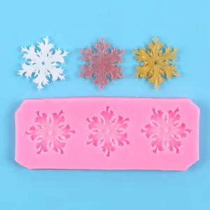Detail of pink snowflake silicone mold with texture and three finished decorative flakes
