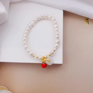 Vista dettagliata del bracciale di perle con ciondoli a forma di cachi rossi