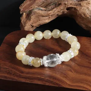Detalle de pulsera de cuarzo rutilado dorado con espaciadores florales plateados.