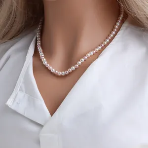 Gros plan d'un élégant collier de perles de nacre multicolores porté avec une chemise blanche