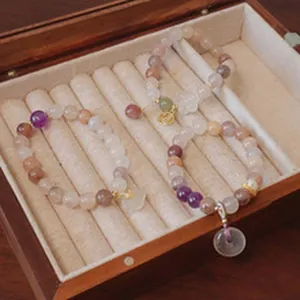 Dettaglio di bracciali in pietre naturali con ciondoli in un portagioie di legno.