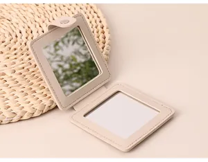 Close-up of a portable beige PU leather foldable makeup mirror with button closure