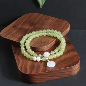 Detailaufnahme eines zweireihigen Armbands aus grüner Jade auf Holzständer