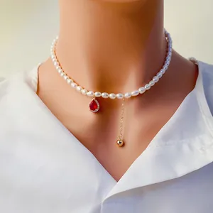 Gros plan détaillé d'un collier de perles avec pendentif goutte rouge et gland