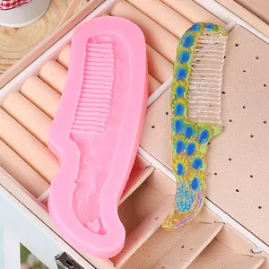 Detailed view of a DIY peacock pattern resin comb next to the pink silicone mold