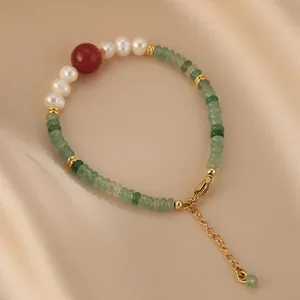 Detailed shot of aventurine and freshwater pearl bracelet with a vibrant red agate bead