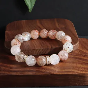 Detailansicht eines Naturstein-Armbands mit Super Seven Kristallen und Goldperlen.