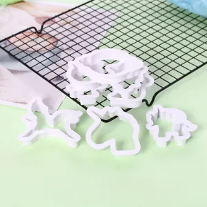 Set aus weißen Einhorn-Ausstechformen aus Kunststoff auf einem schwarzen Backgitter