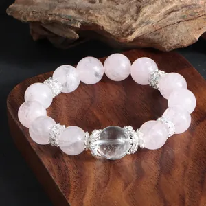 Gros plan d'un bracelet en quartz rose et cristal avec des intercalaires floraux argentés.