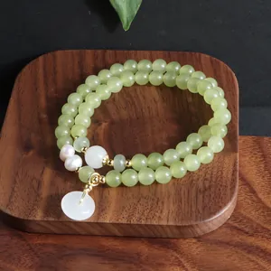 Detailansicht eines grünen Jadeperlenarmbands mit weißen Perlen auf einem Holzblock